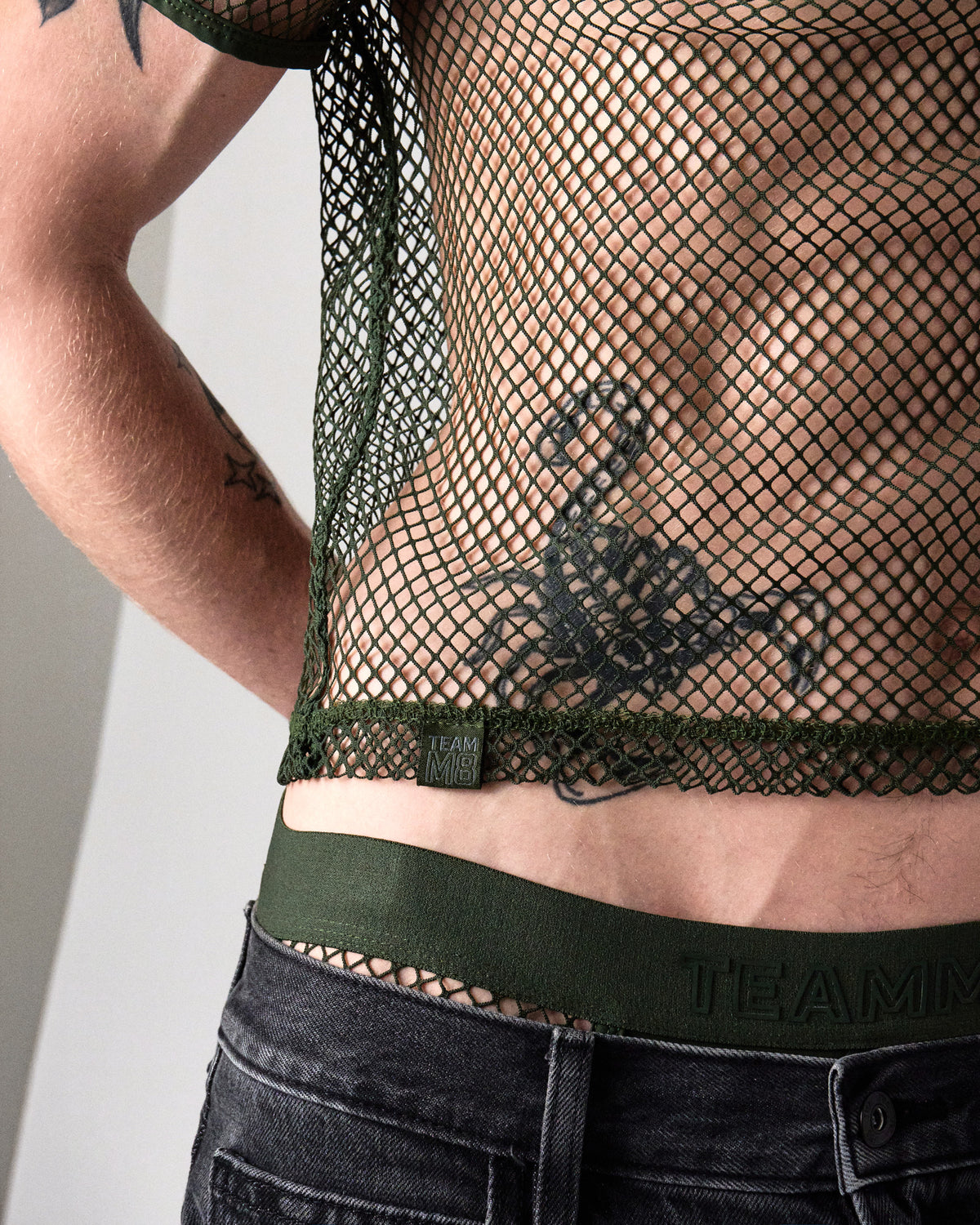 Edge Net Cropped Tee in Forest, close-up of the cropped hem and TEAMM8 label tab