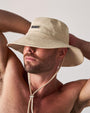 Man wearing a beige bucket hat against a neutral background